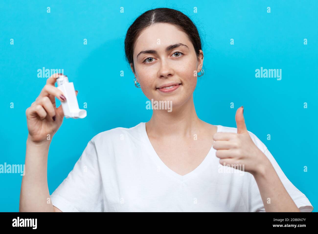 Portrait of a female smiling doctor holding an inhaler in her hand and ...
