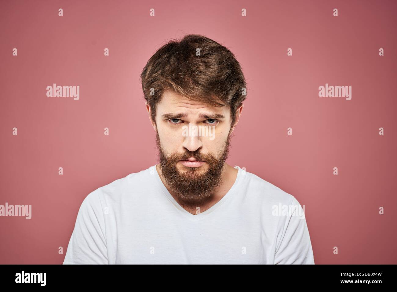 Emotional bearded man in white T-shirt discontent pink background Stock ...