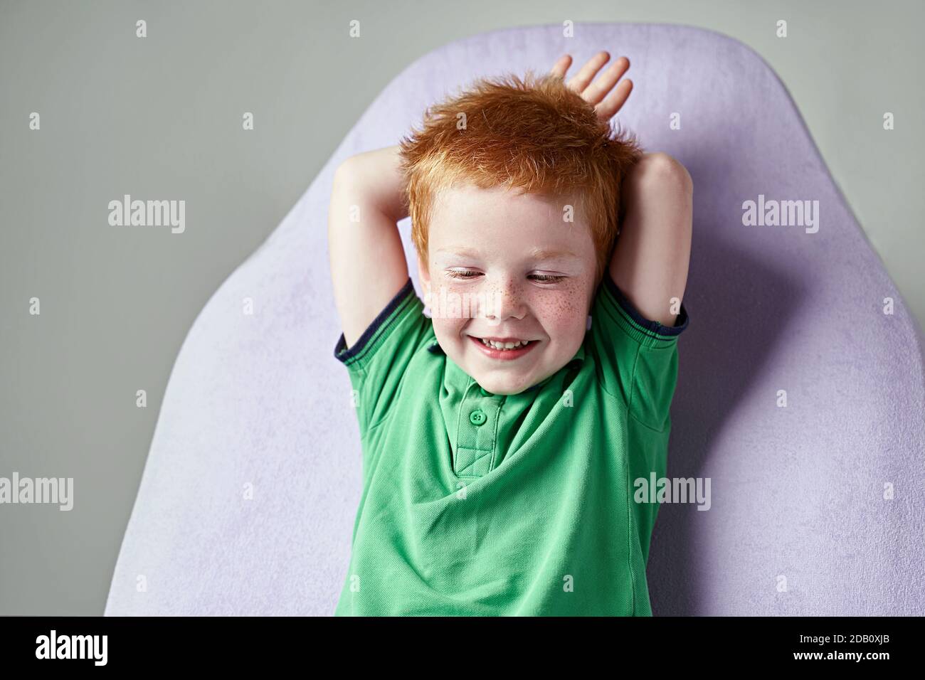 Cute red haired freckled little boy in green t-shirt waiting for doctor in medical office Stock Photo