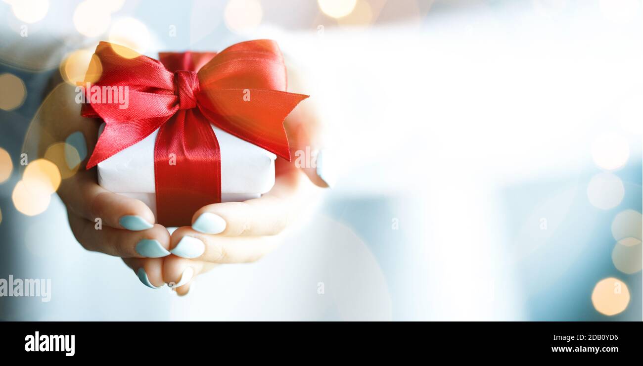 Hands holding little gift with red bow Stock Photo