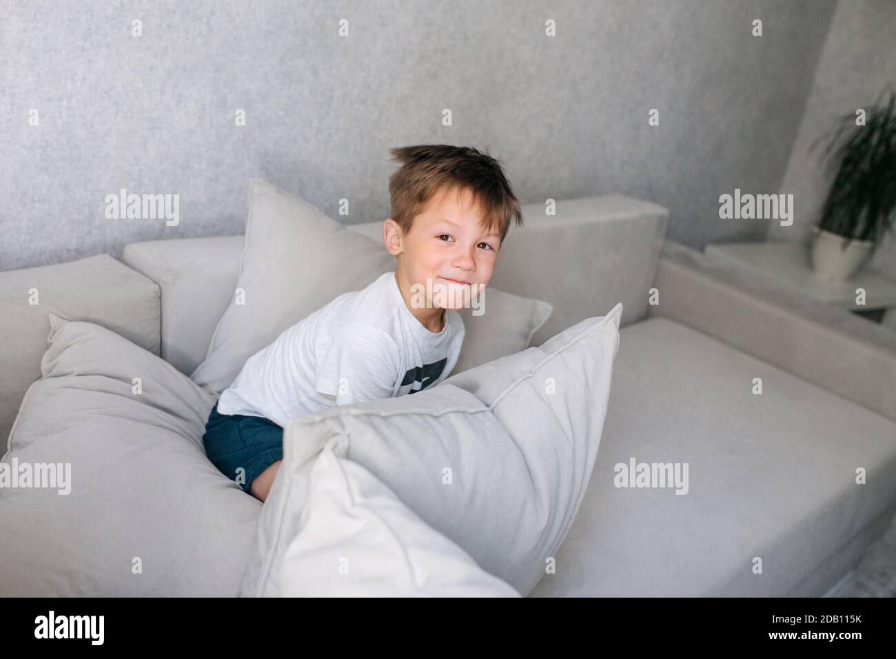 little boy having pillow fight on sofa at home Stock Photo
