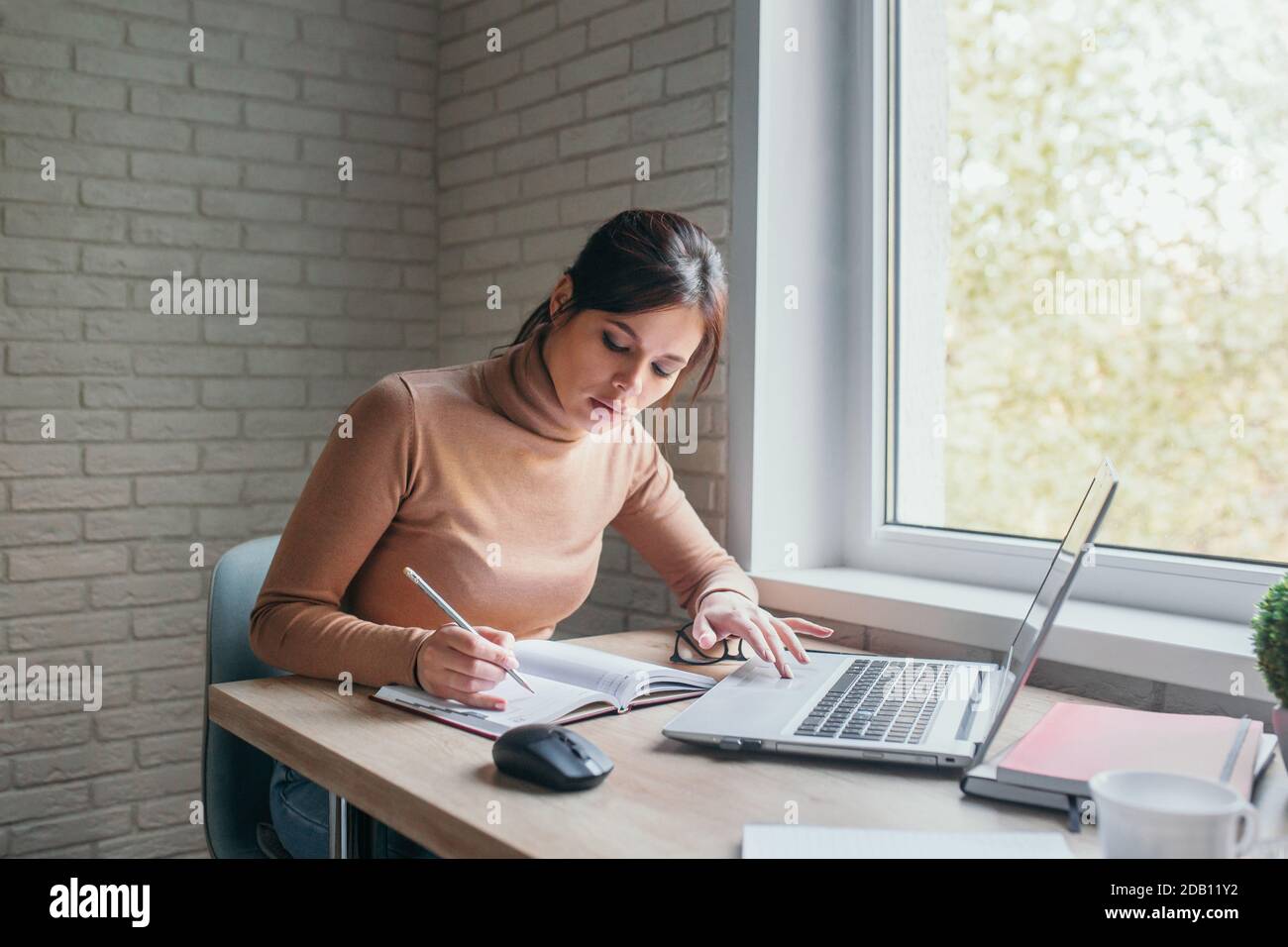 Happy hispanic young woman wearing glasses using laptop computer working studying at home office Stock Photo