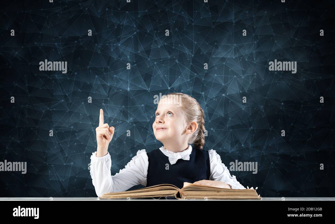 Smiling little girl sitting at desk with open book Stock Photo - Alamy