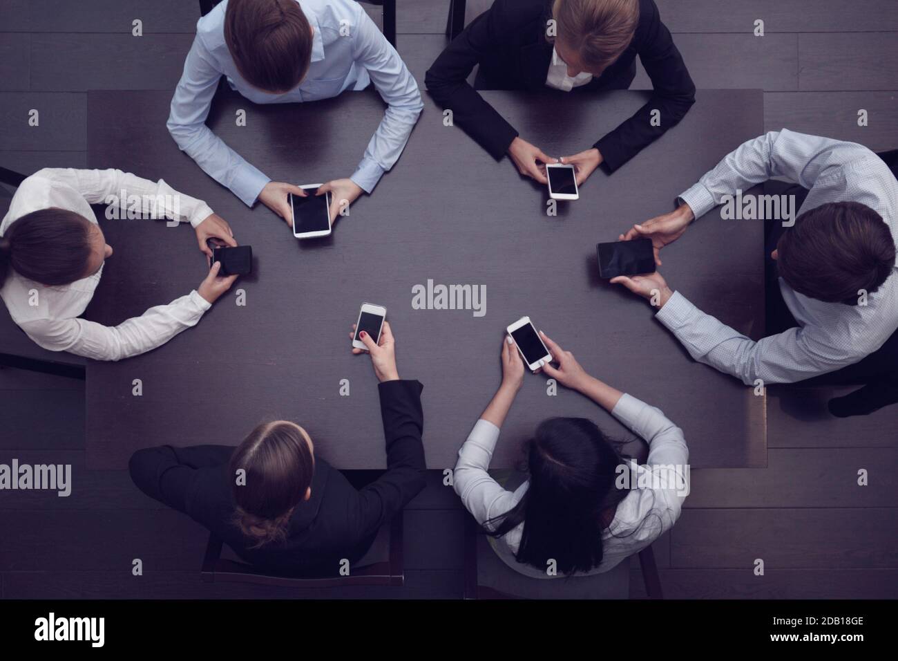 Business people with smart phones sitting around the table, top view Stock Photo