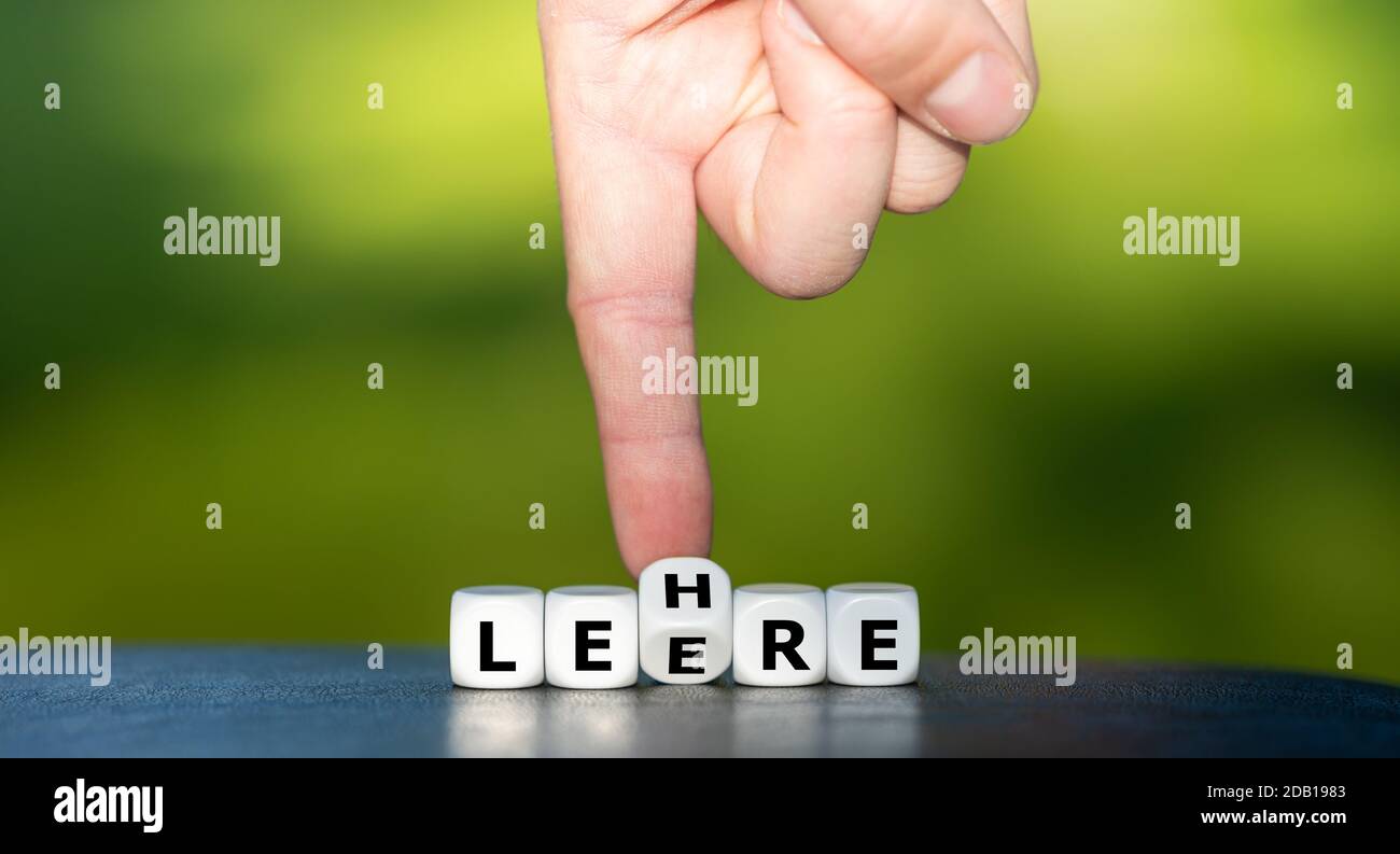 Hand turns dice and changes the German word "Leere" (emptiness) to "Lehre" (education). Stock Photo