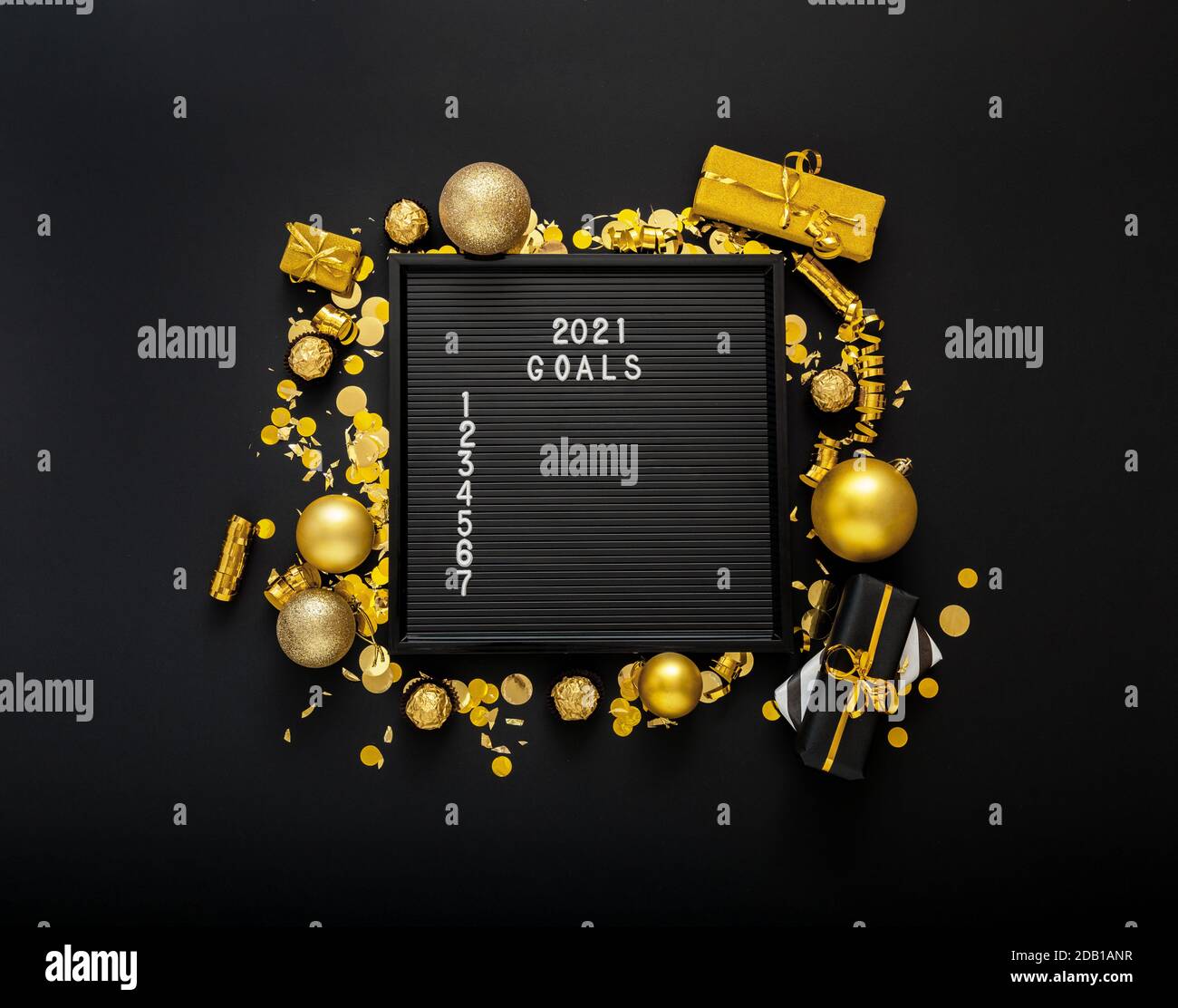 Numbered list of 2021 Goals on black Board in frame made of gold festive decor, gift boxes, confetti. New year eve 2021 goals, resolution check list w Stock Photo