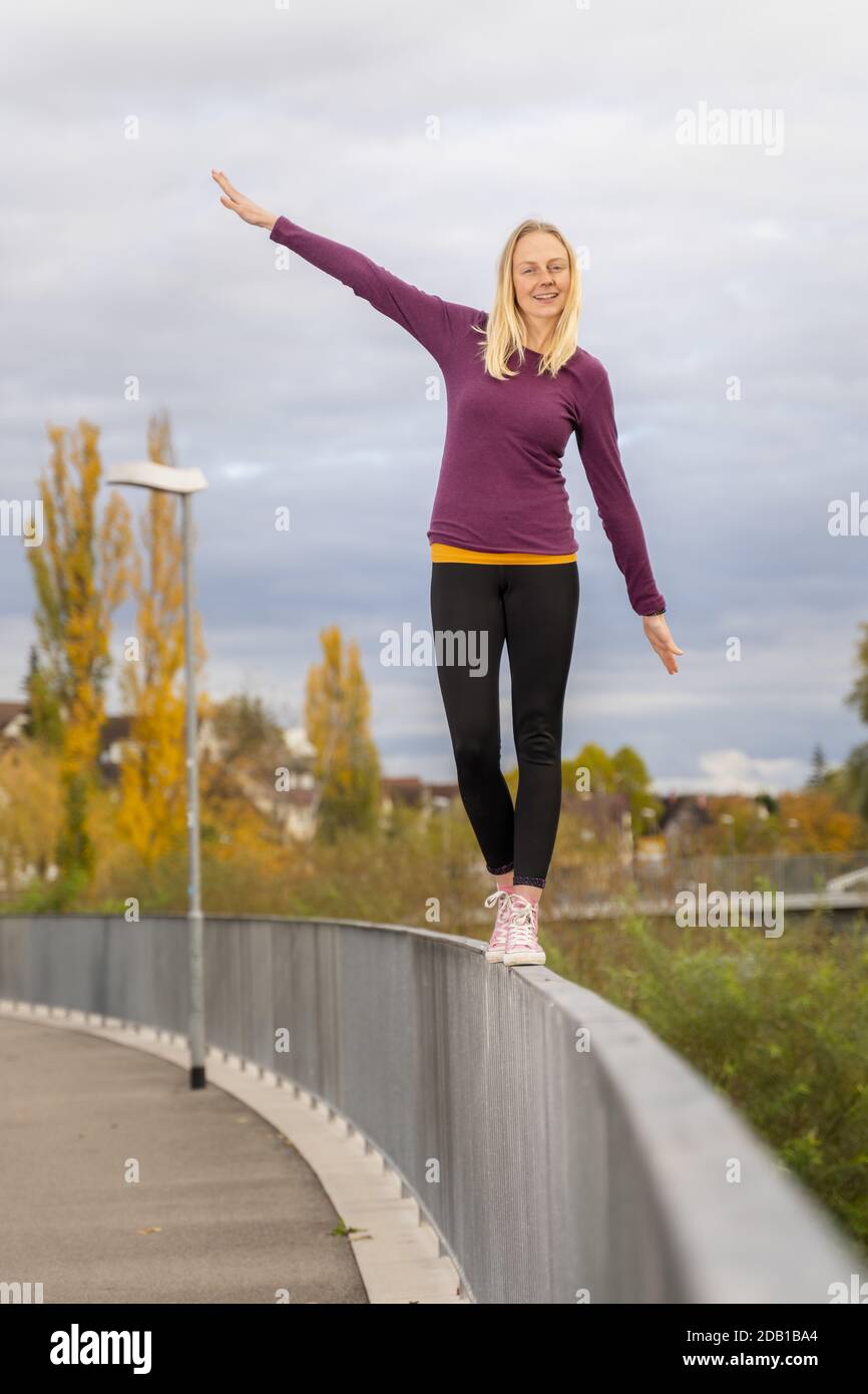 Balancing On Railing young woman balancing on a handrail, urban scenery in autumn Stock ...