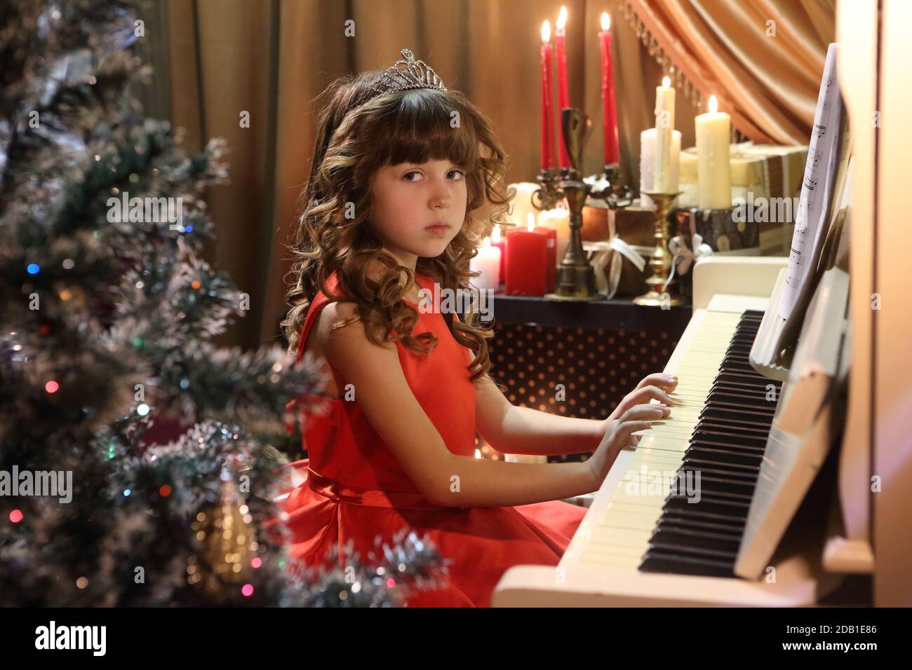 Beautiful girl in a red dress plays the piano Stock Photo - Alamy