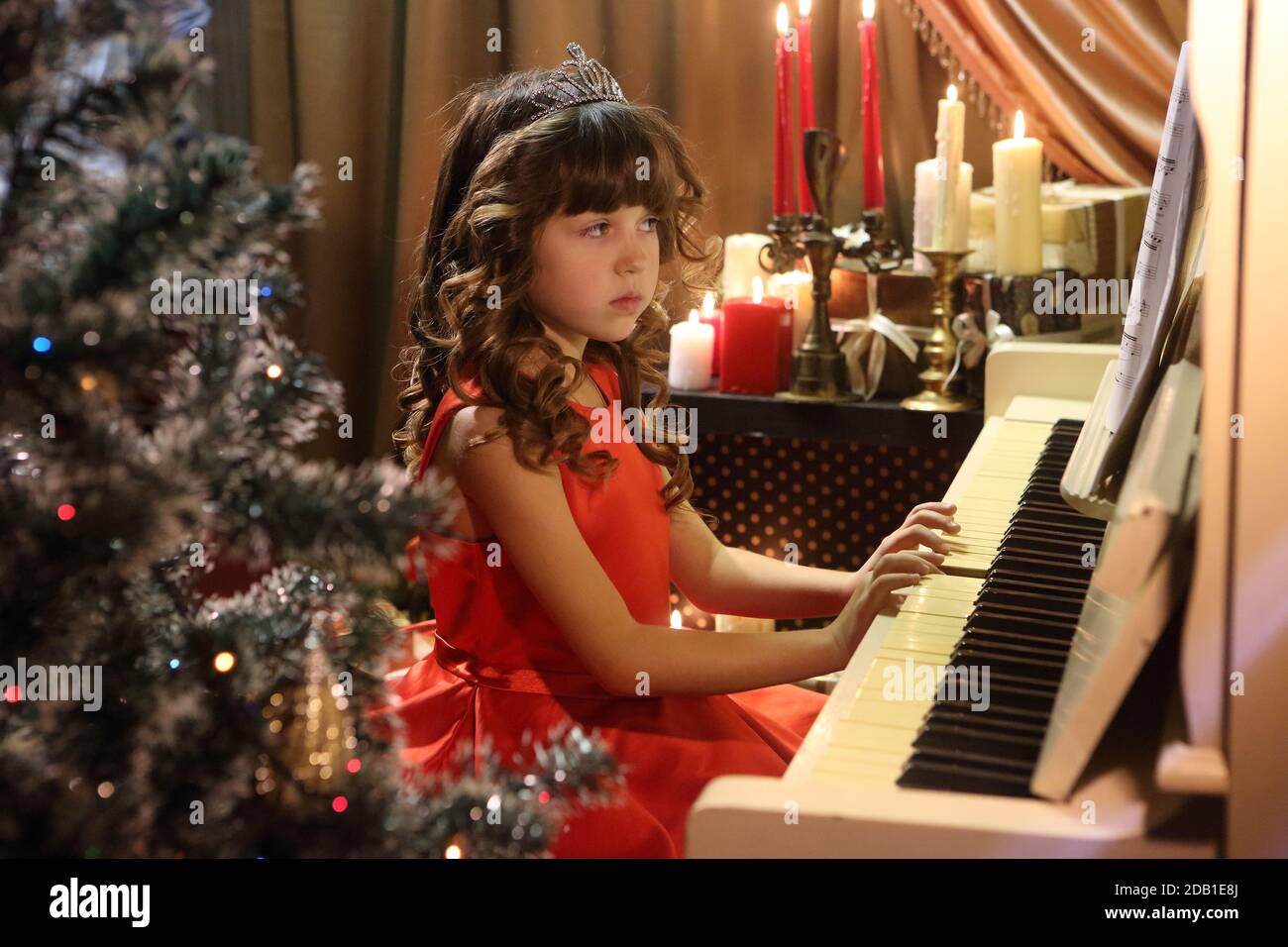 Beautiful girl in a red dress plays the piano Stock Photo - Alamy