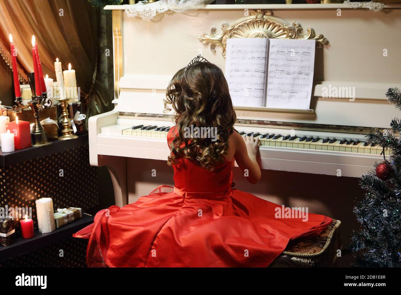 Beautiful girl in a red dress plays the piano Stock Photo - Alamy