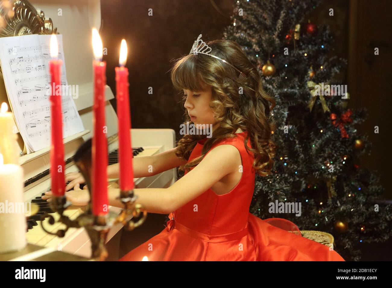 Beautiful girl in a red dress plays the piano Stock Photo - Alamy