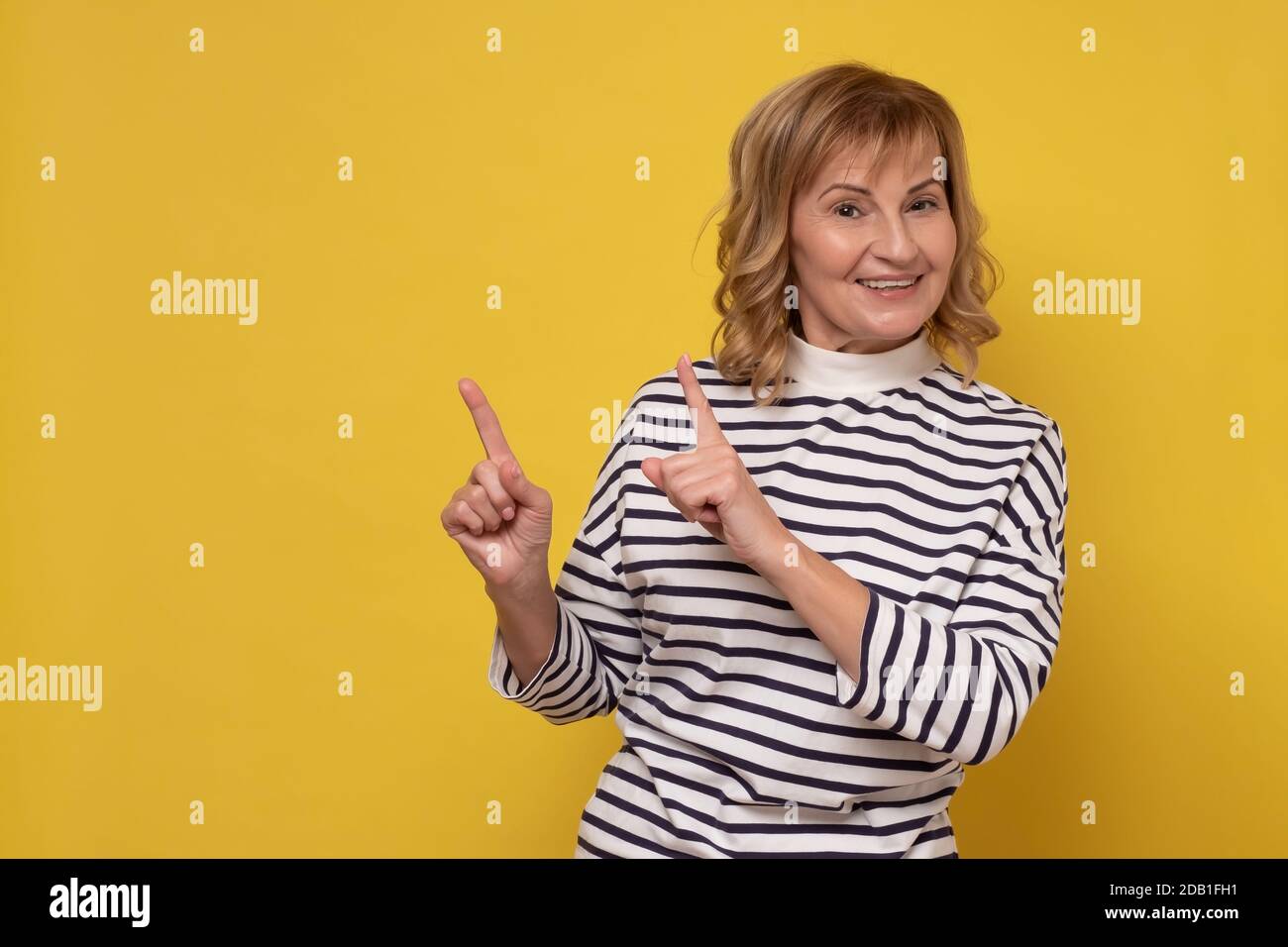 Mature caucasian woman with finger point aisde. Stock Photo