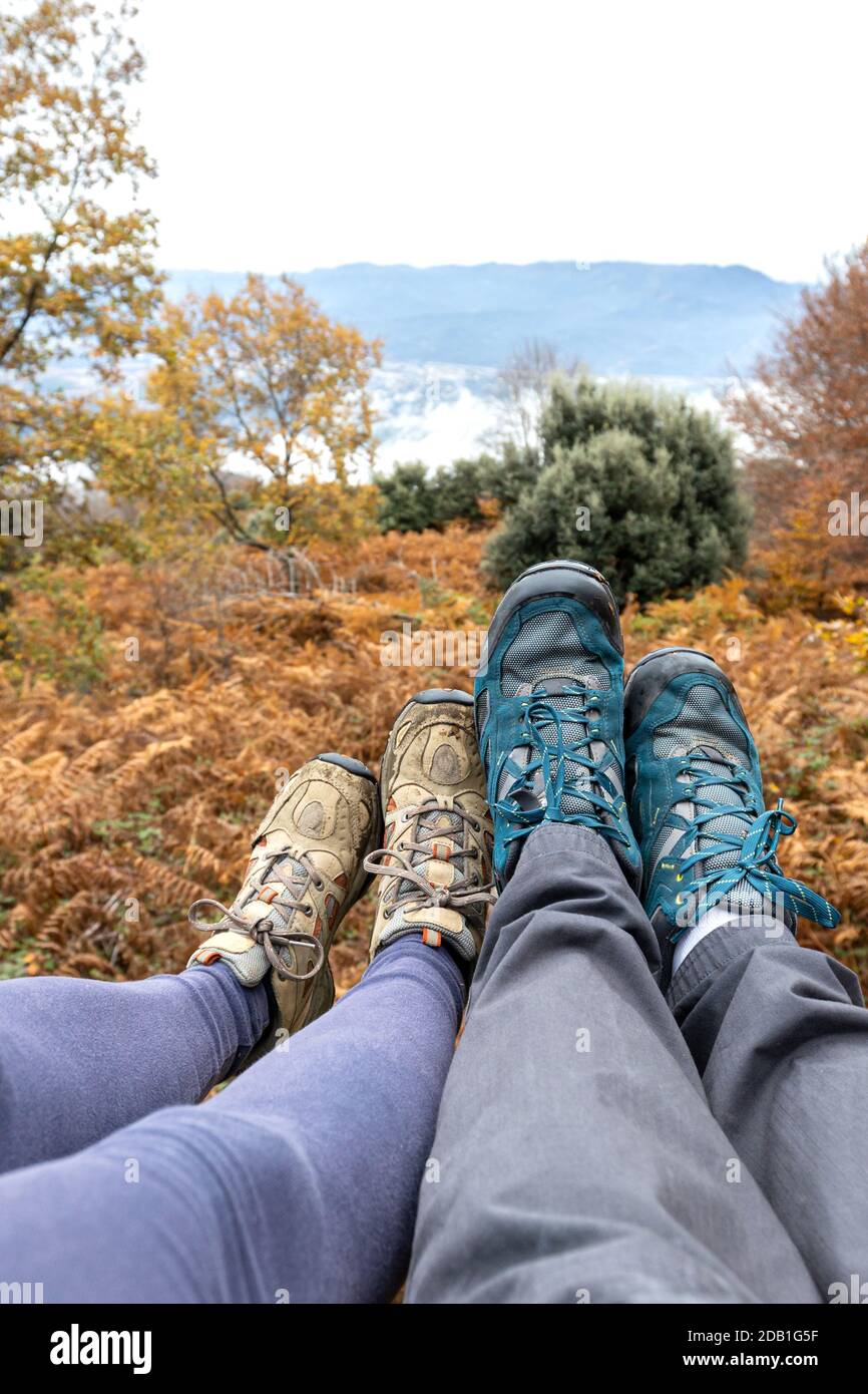 Couple sitting in the forest, only the feet and shoes are visible. Unrecognizable persons. Stock Photo