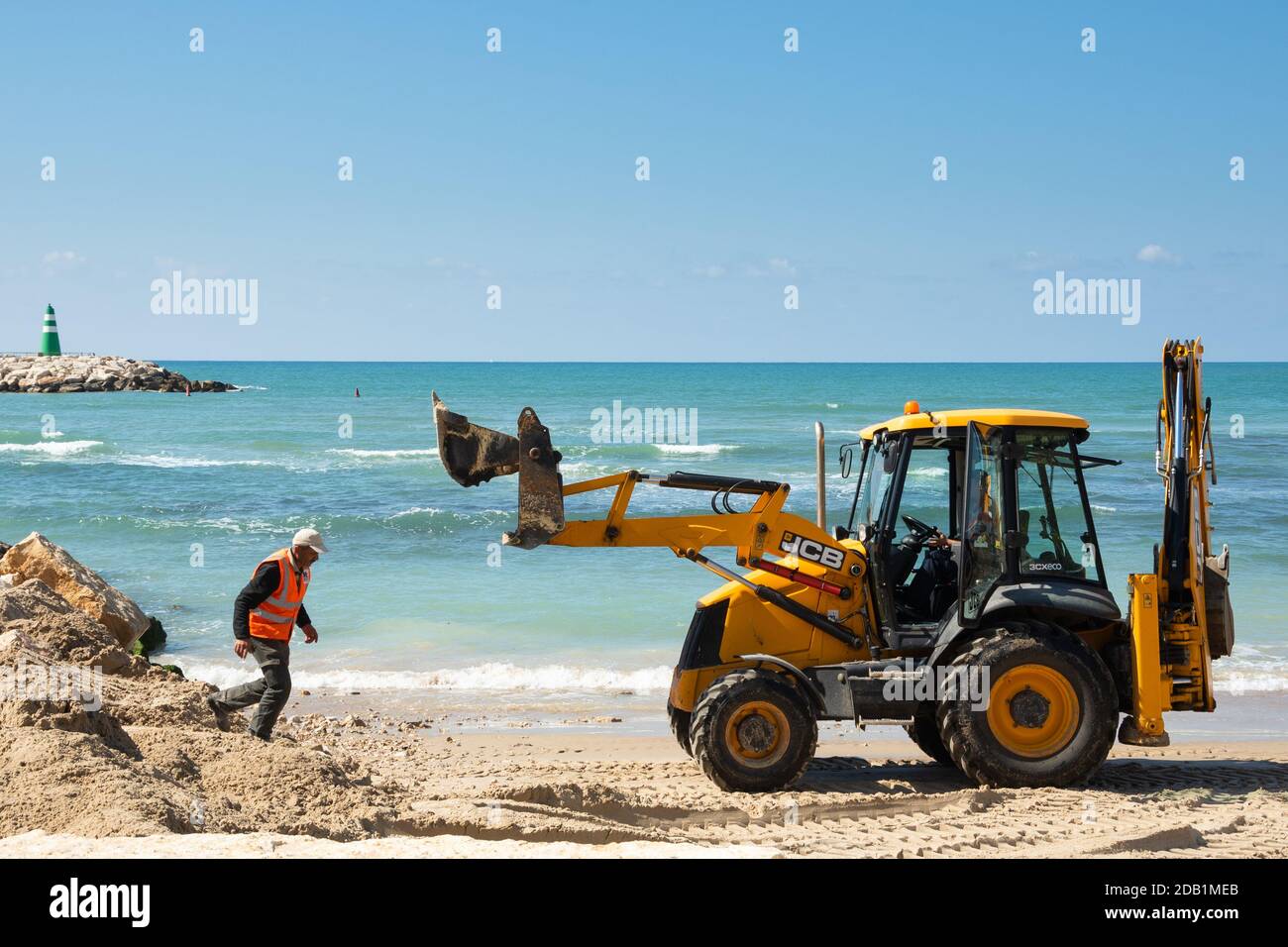 TEL AVIV, ISRAEL - MARCH 6, 2019: Beach industrial scene. Workers making repairs at the beach with digger . Stock Photo