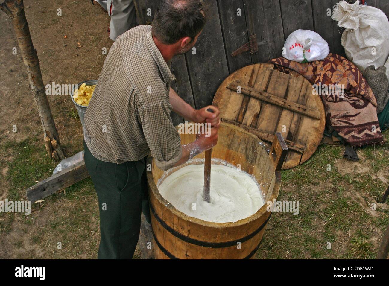 Maramures, Romania. Shepherd making butter the old-fashioned way, manually churning the cream in a wooden barrel. Stock Photo