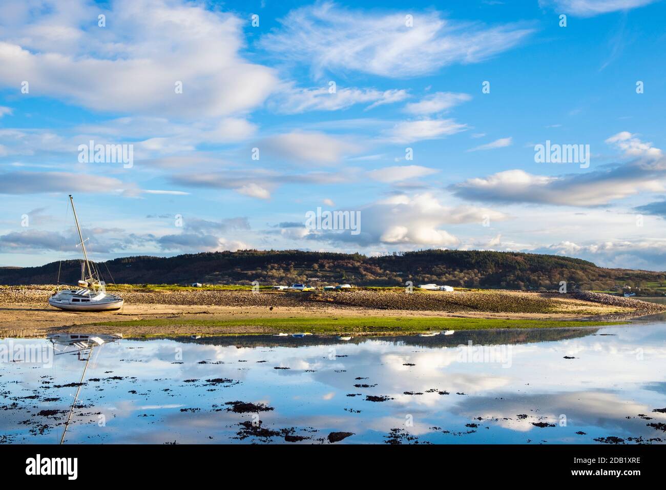 Tranquil scene with clouds reflected in calm sea water at high tide on Welsh coast in Red Wharf Bay, Isle of Anglesey, Wales, UK, Britain Stock Photo