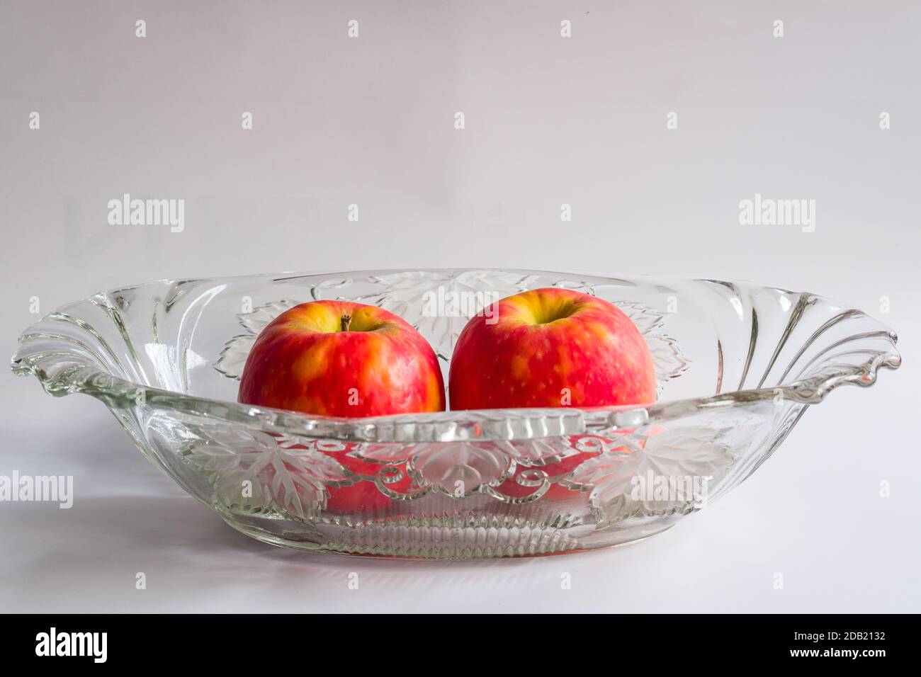 Still life with two red apples in an antique glass bowl for fruits