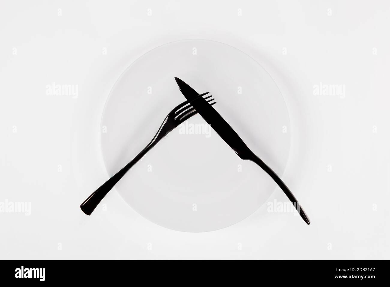 Cutlery language, dining etiquette. Did not like. White ceramic round plate with knife anf fork isolated on white, top view. Stock Photo