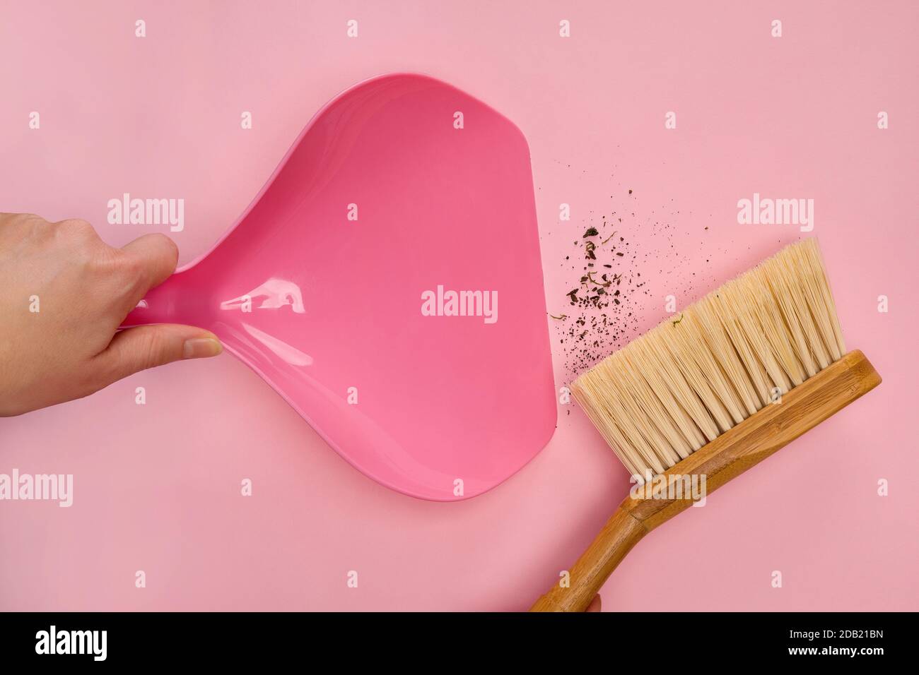 Woman with wooden hand broom and dustpan sweeping dirty floor. Cleaning