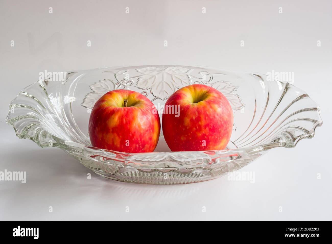 Still life with two red apples in an antique glass bowl for fruits