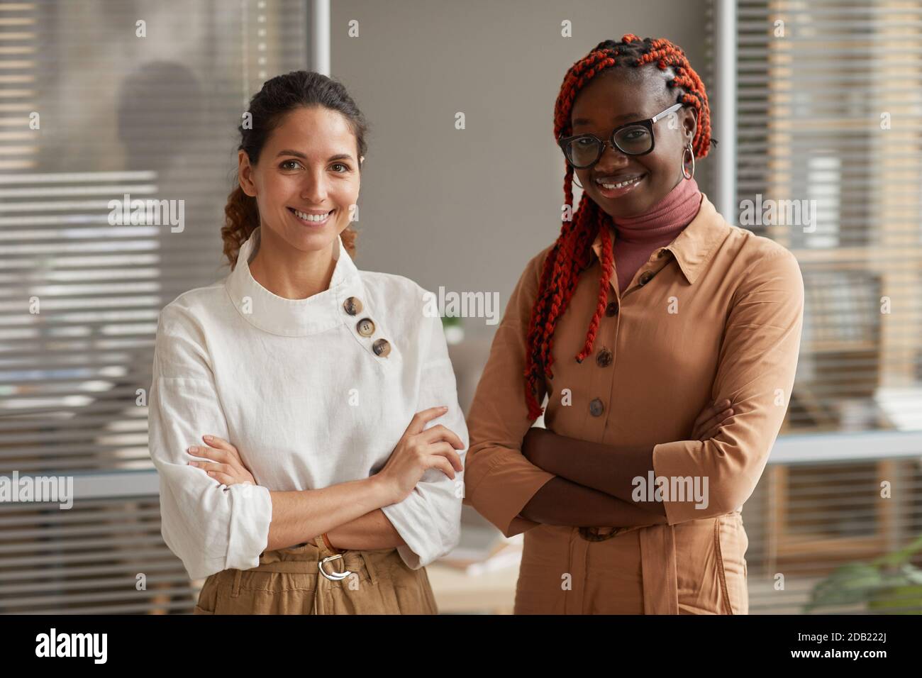 Waist up portrait of two successful young businesswomen smiling at ...