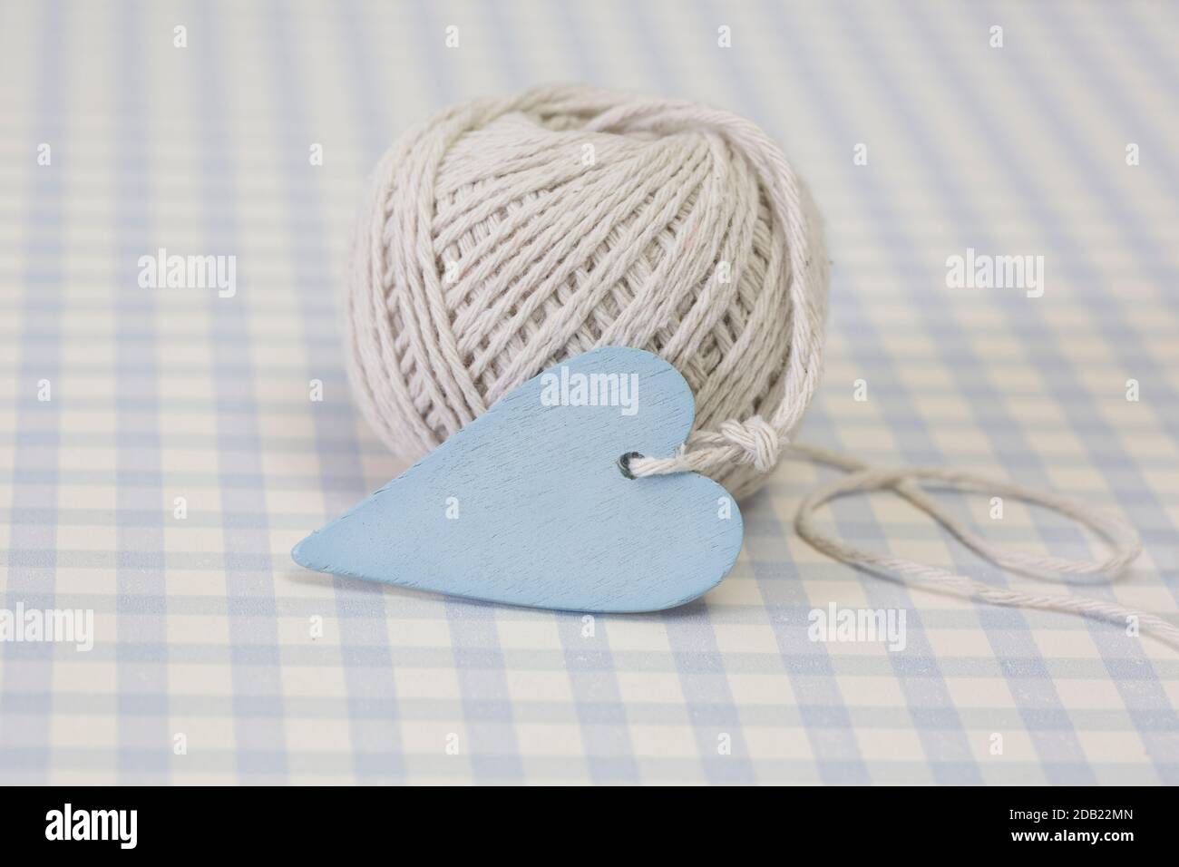 spring still life with heart and a roll of twine in pastel blue colors on blue checkered background Stock Photo