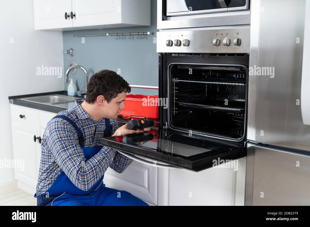 Male Technician In Overall Installing Oven In Kitchen Stock Photo - Alamy