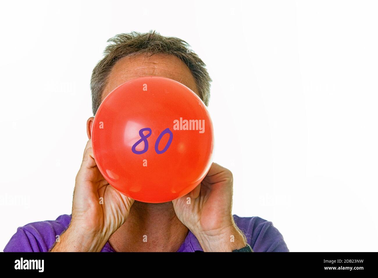 Man blowing red balloon with number 80 Stock Photo