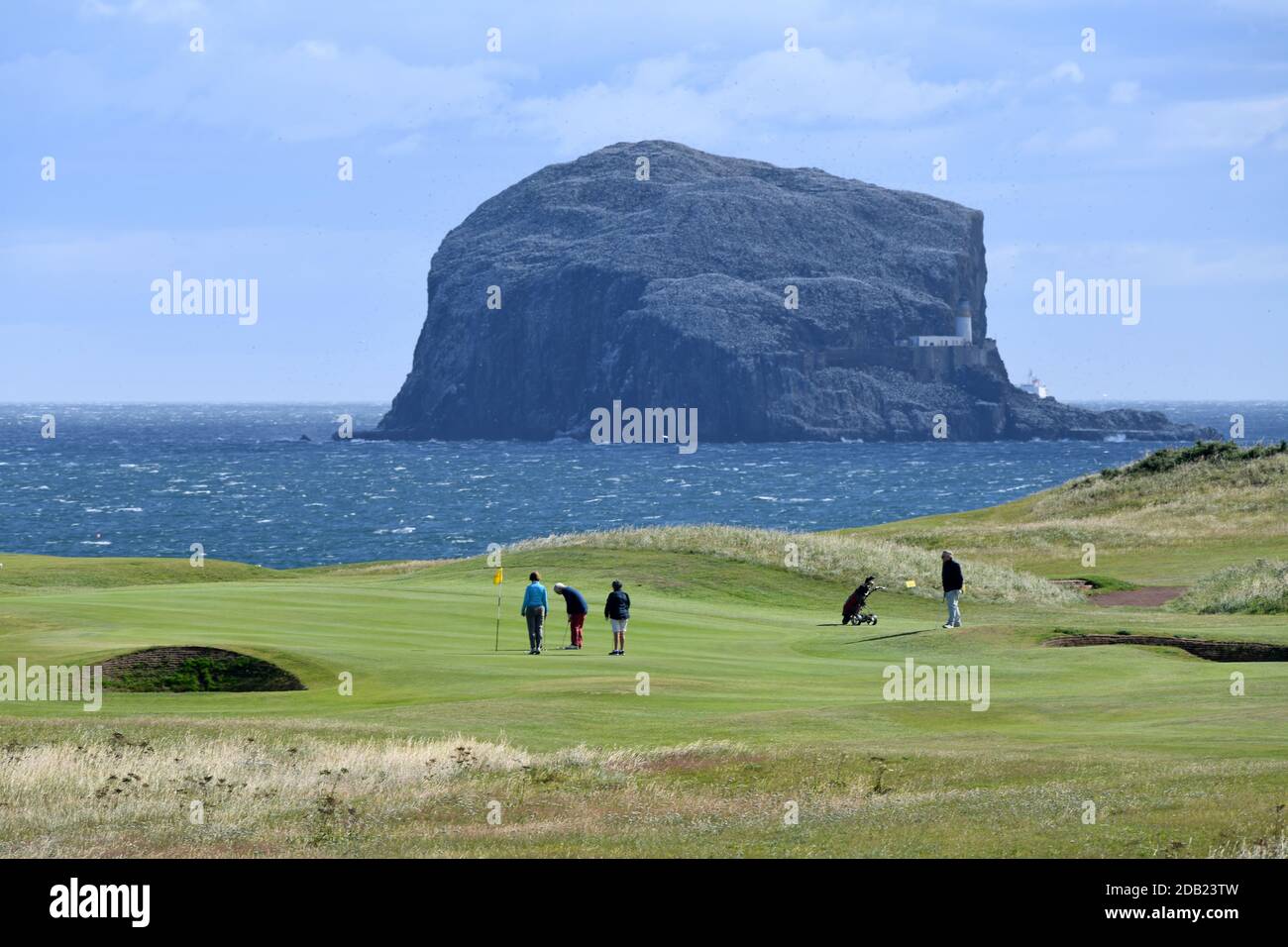 Picture shows golfers playing a round of golf at Glen Club, North Berwick, Scotland, with the backdrop of The Bass Rock and The Firth of Forth. Stock Photo