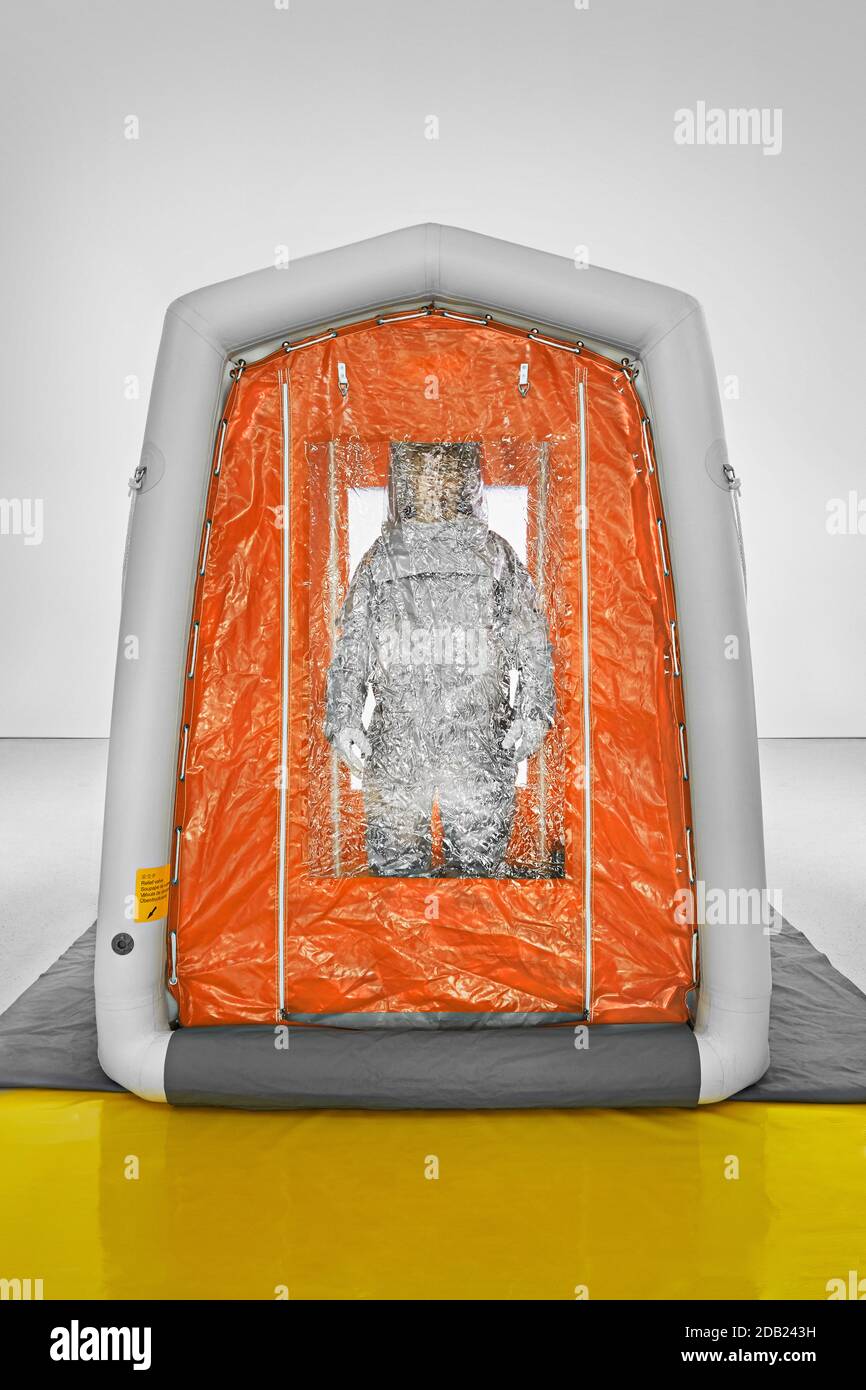 Man wearing a decontamination suit standing in decontamination tent. Stock Photo