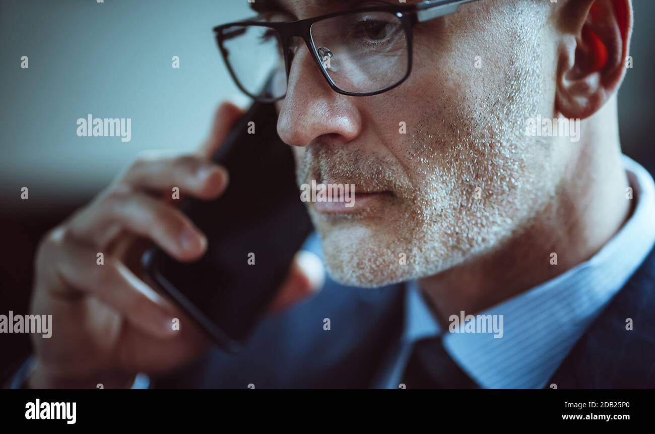 Handsome businessman talks on mobile phone. Close up portrait of Caucasian man with gray stubble answering the call. Business concept Stock Photo
