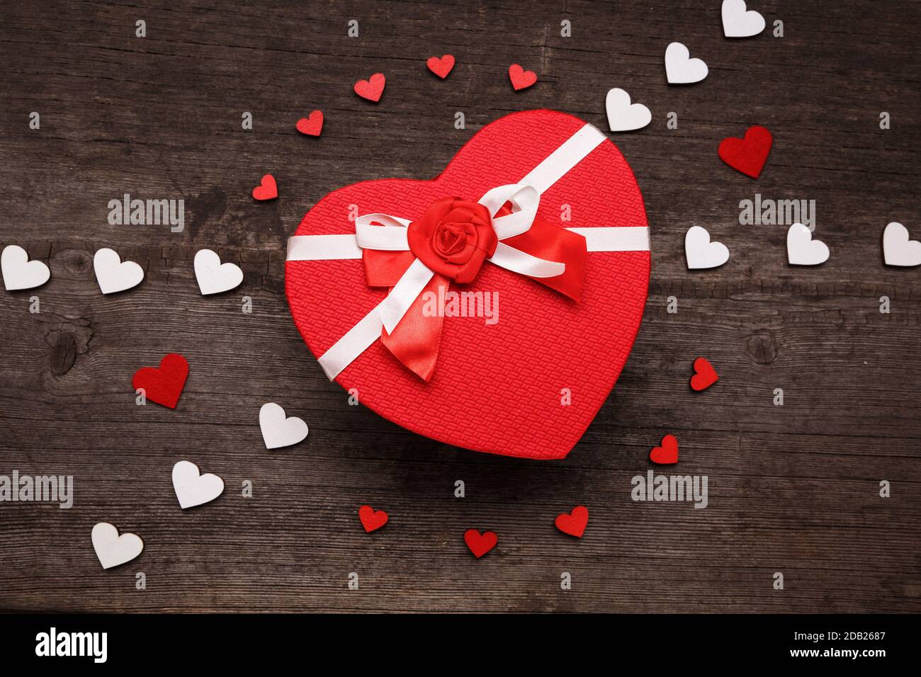The cover of the box in the shape of a heart. Composition with red and white hearts on a wooden background. Valentines day concept with hearts and gif Stock Photo