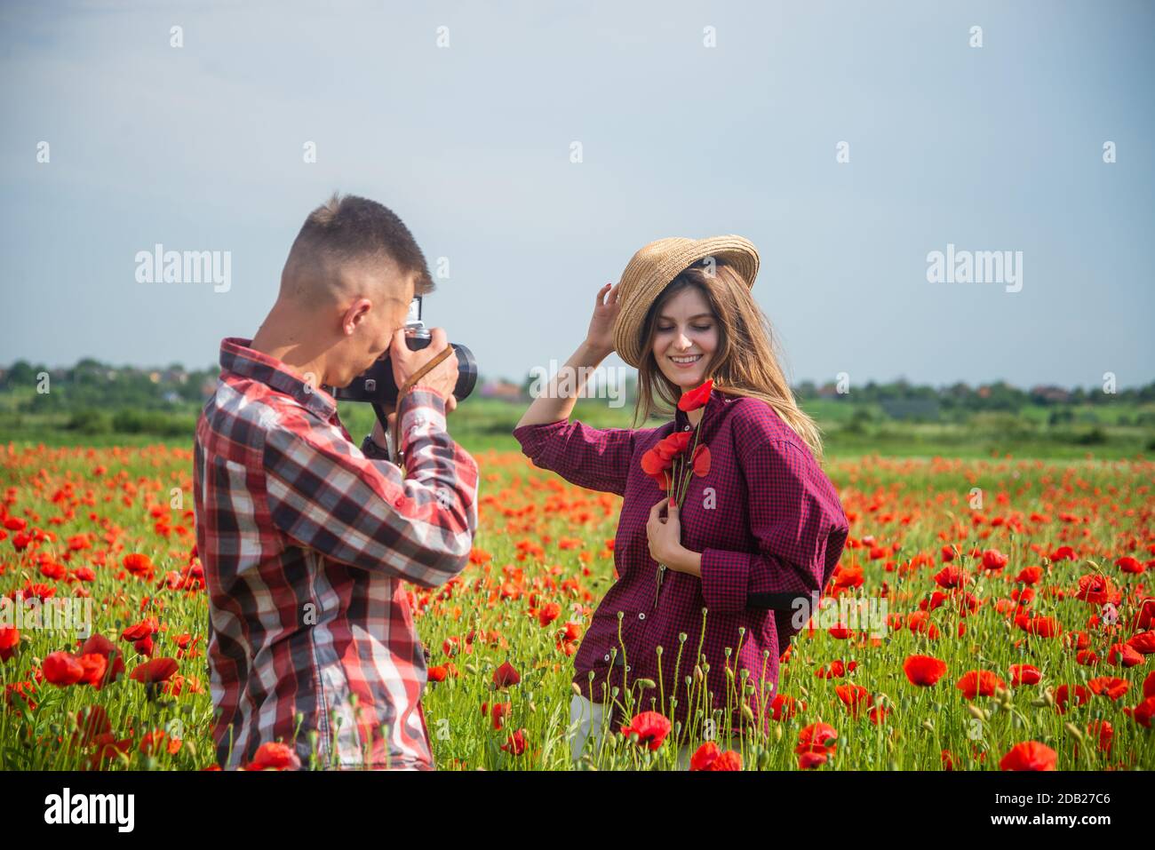 Honeymoon trip. happy relations. girl and guy in field with camera. romantic couple photographing in red poppy flowers. family summer vacation. happy man and woman in love enjoy spring weather. Stock Photo