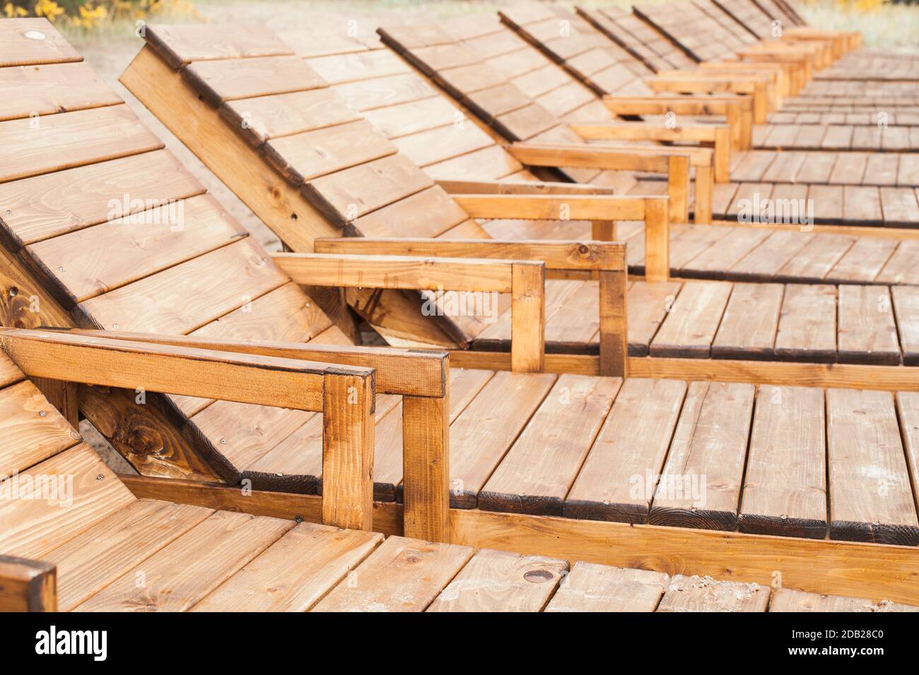 Empty wooden sun lounges stand in a row. Outdoor resting photo Stock Photo