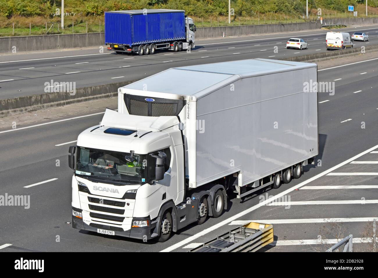Clean all white supply chain business delivery lorry truck transport  & articulated trailer fitted with Carrier chiller cooler driving on UK motorway Stock Photo