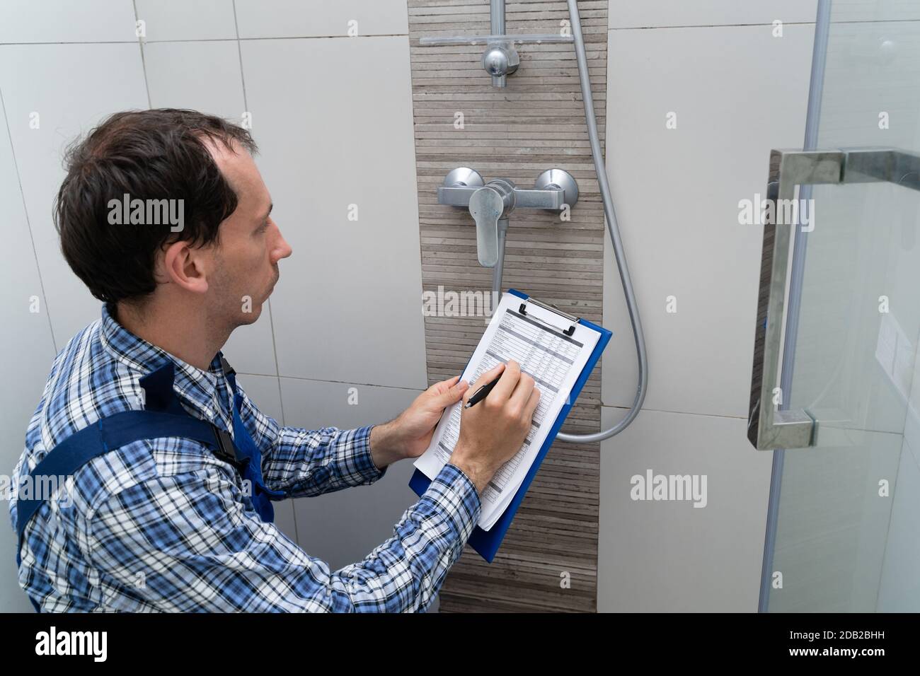 Young Male Plumber Checking Faucet In Shower Stock Photo