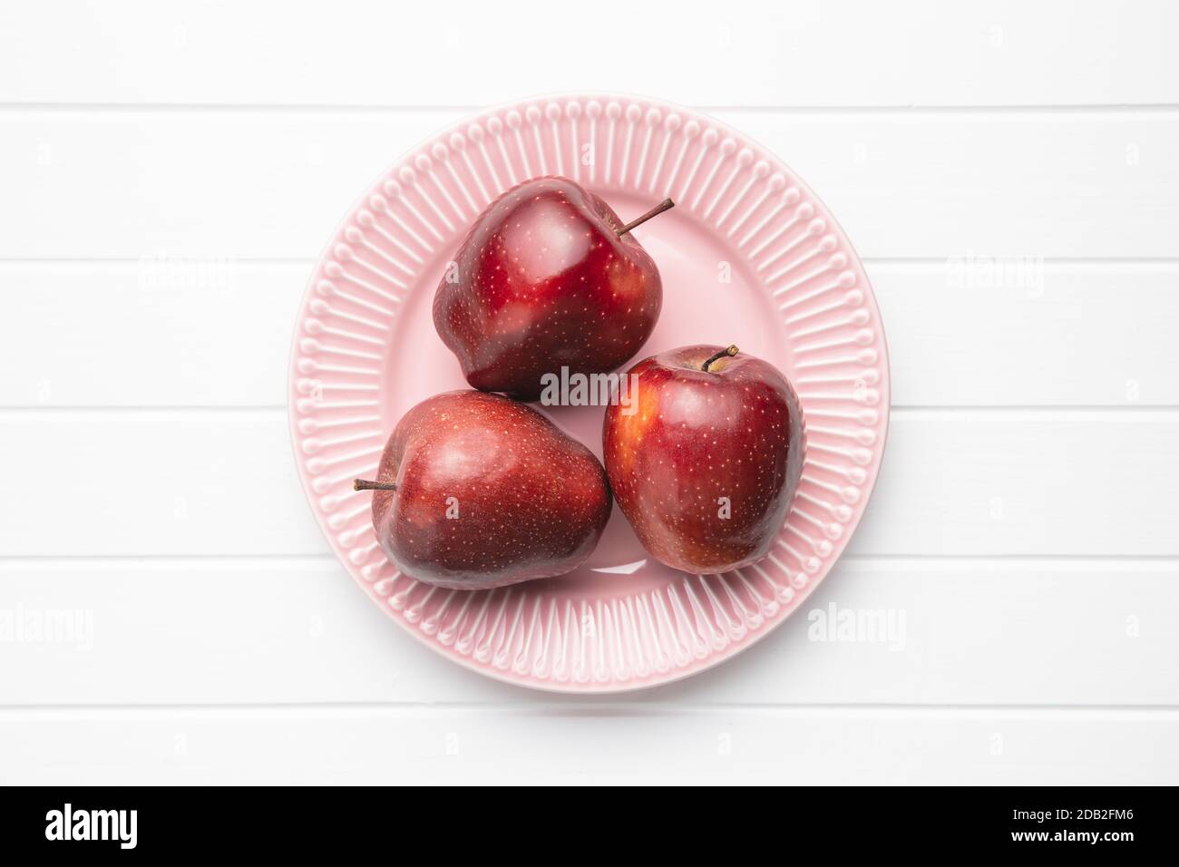 Three ripe red apples on plate. Top view. Stock Photo