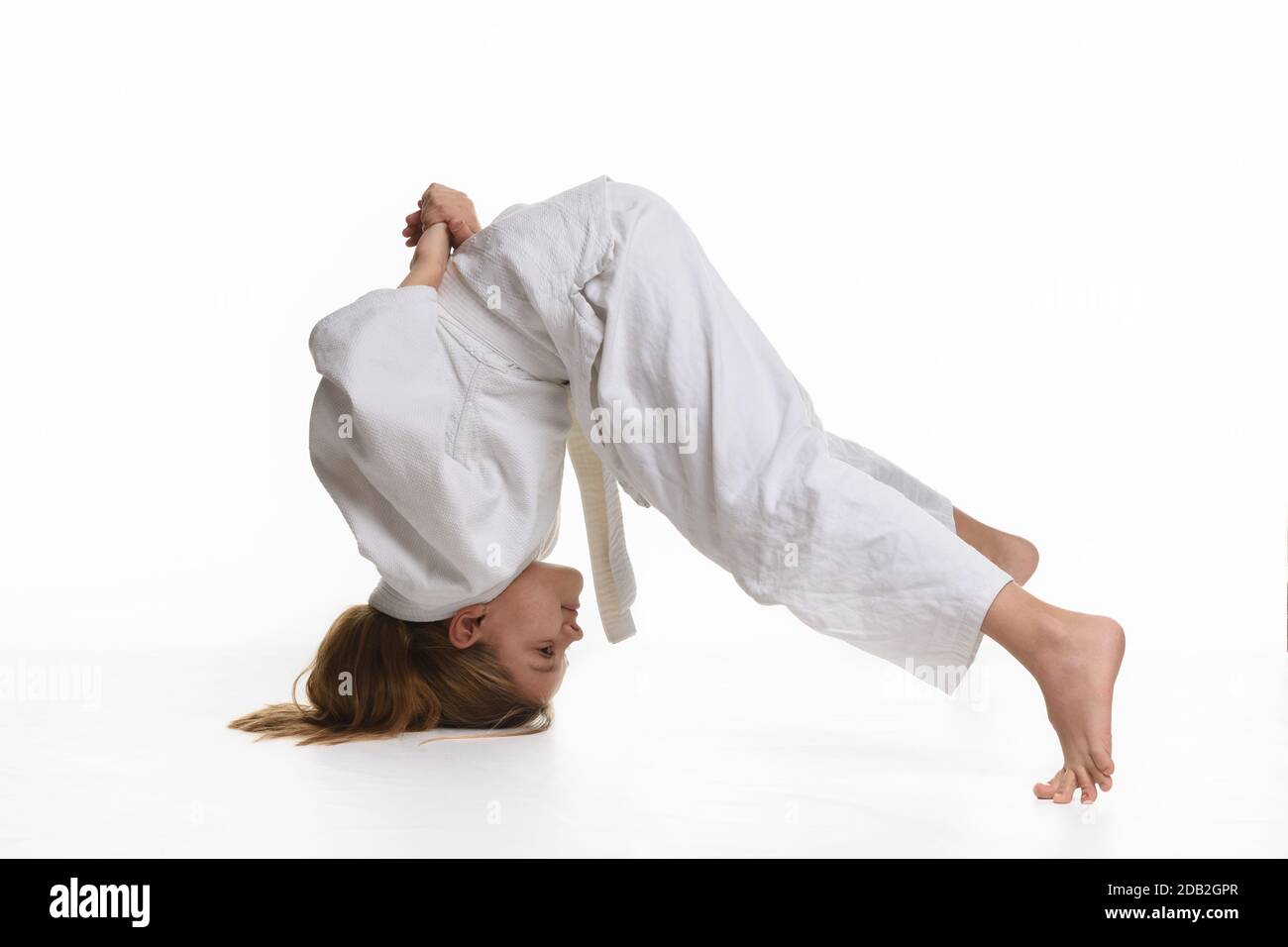 Girl judo student performs exercise sticking to head and legs Stock