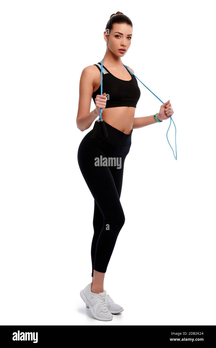 Slim and strong sportswoman holding skipping rope around her neck against white isolated background. Stock Photo