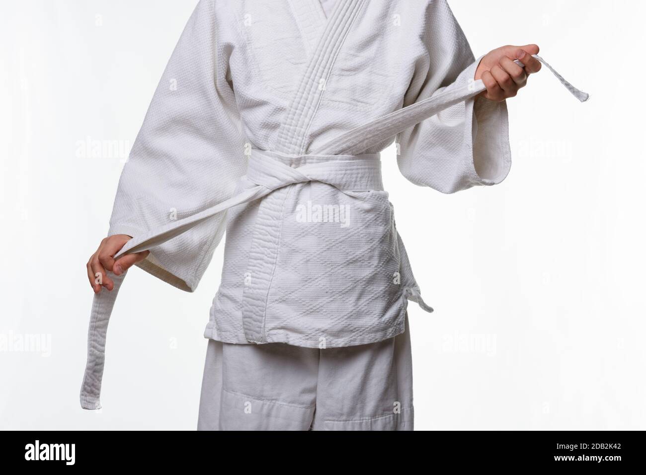 Stages of correct tying of the belt by a teenager on a sports kimono, step seven Stock Photo