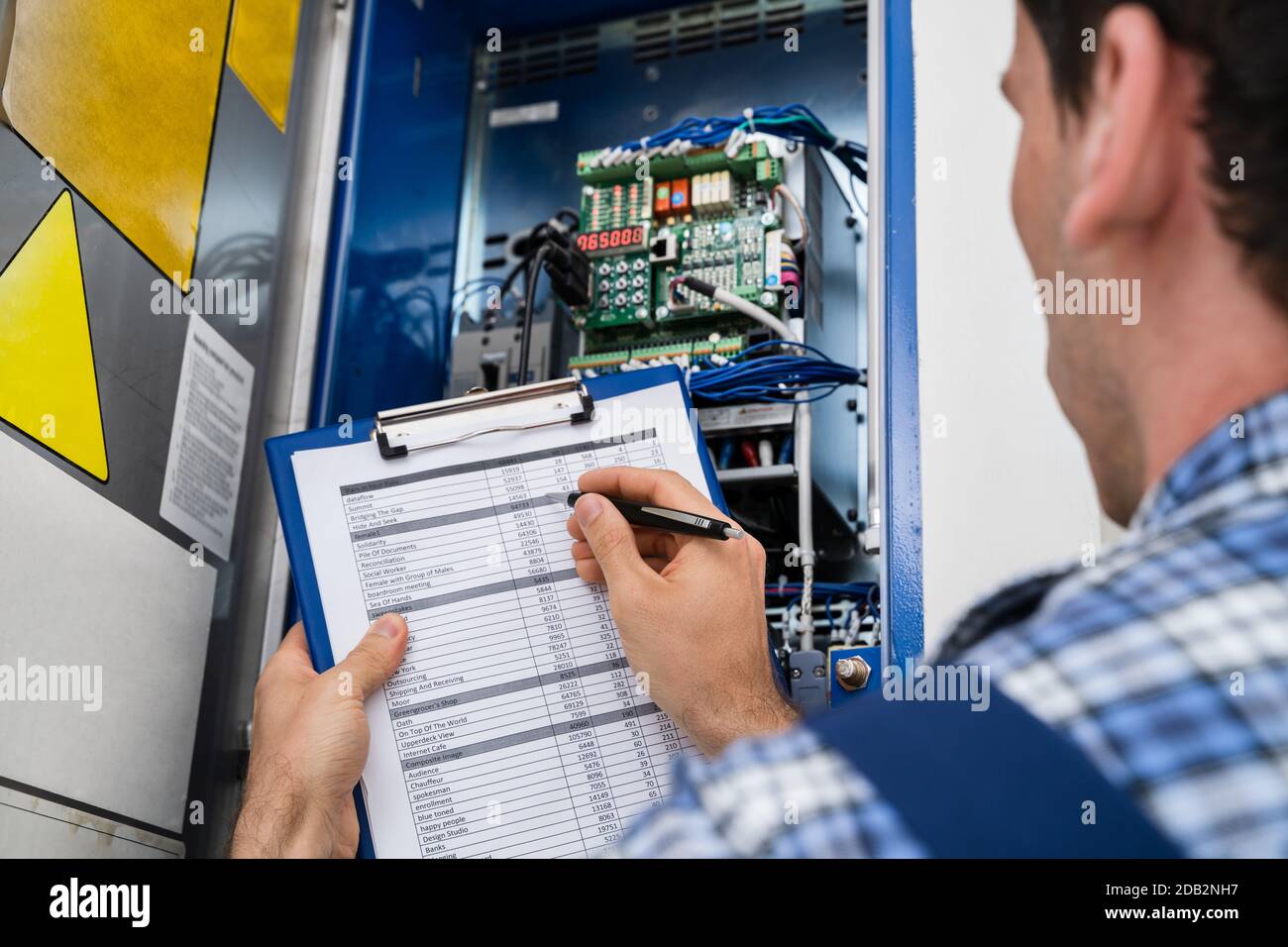 Cropped Image Of Male Electrician Holding Clipboard While Examining Fusebox Stock Photo