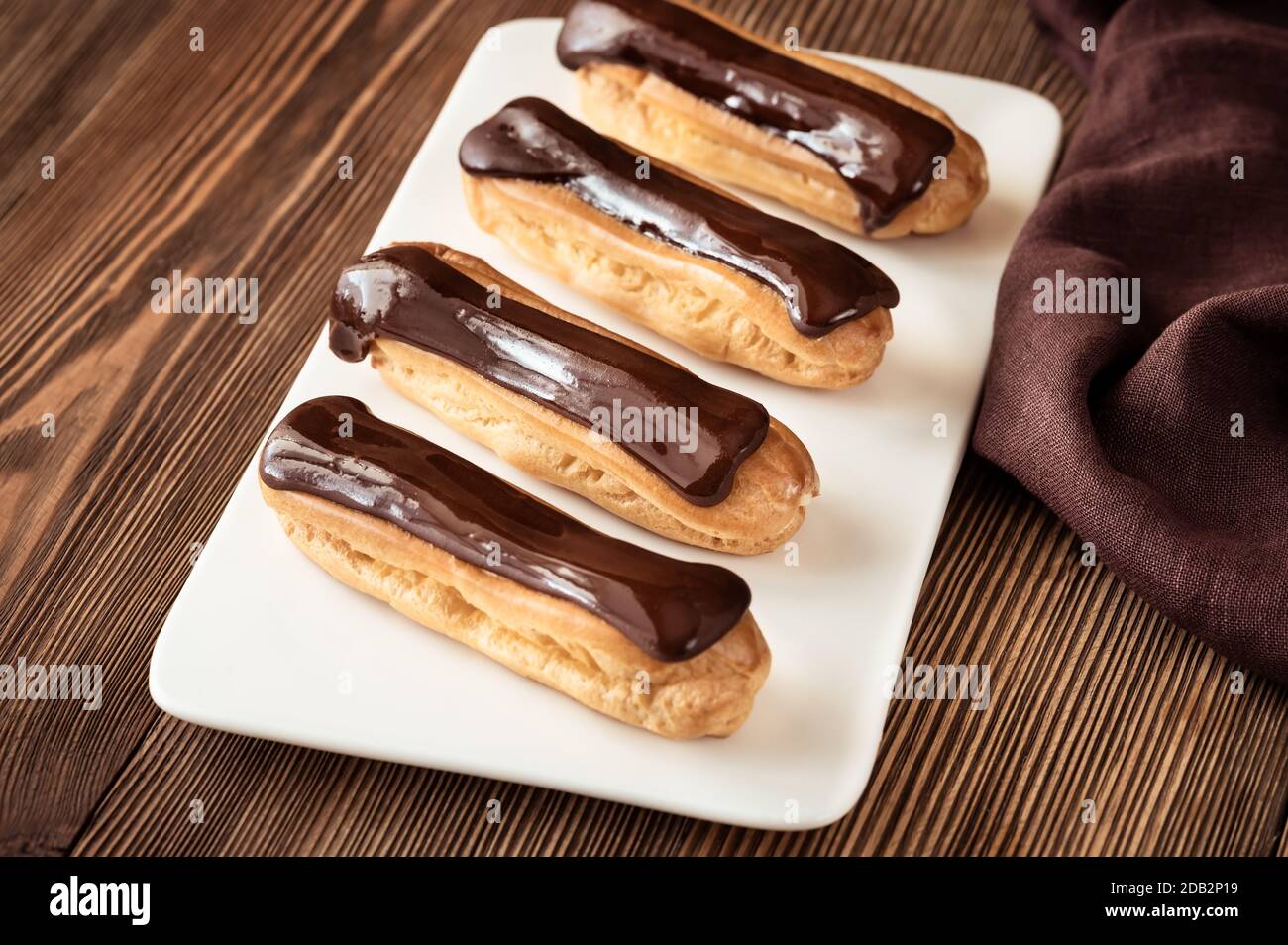 Eclairs with chocolate topping on serving plate Stock Photo