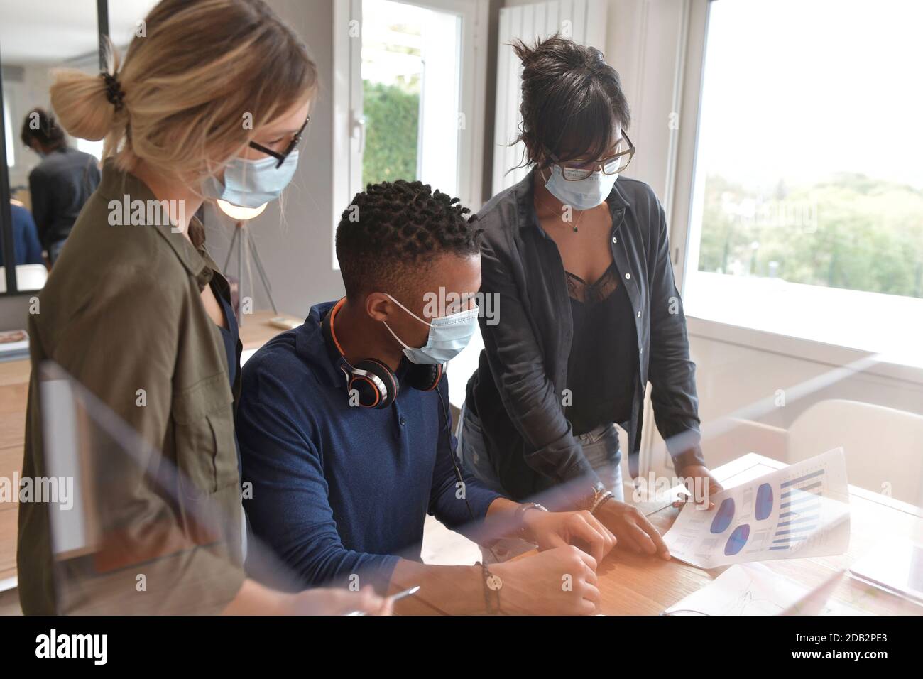 Coworkers in open space office, protected with plexiglas during 19-ncov pandemic Stock Photo