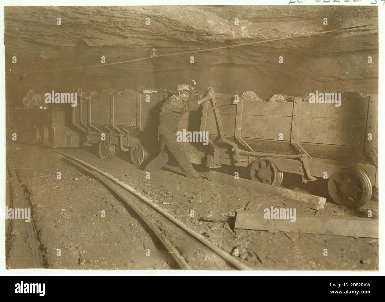 Boy braking on motor train 10 hrs. a day. Where mining, loading, etc. is done by machinery. Live wire above is sometimes not higher than a man's head. Location: Gary, West Virginia.. Stock Photo