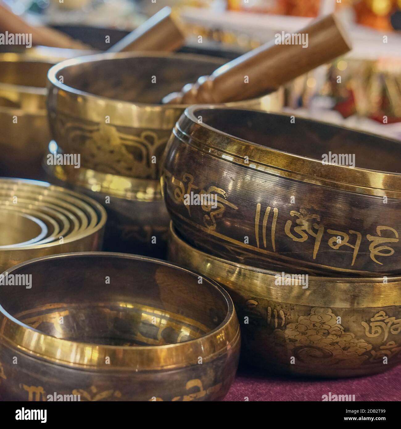 Blurred photo of tibetan healing singing bowls with selective focus to one with mantra sanskrit engraving pattern. Meditation instrument Stock Photo