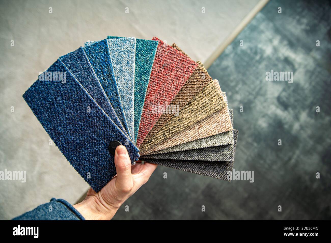 the man chooses the color of the new carpet according to the pattern