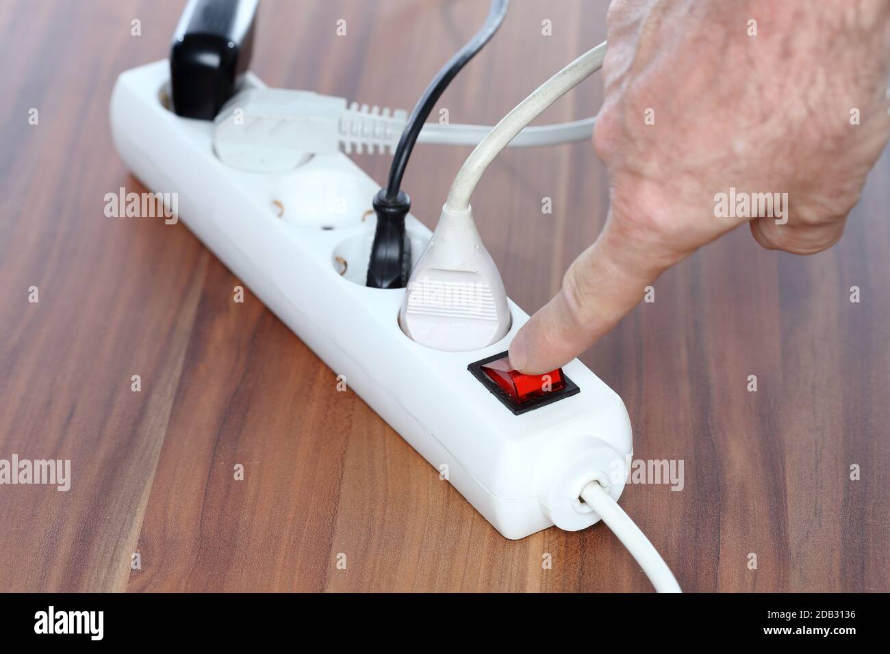 switching off a white plug socket with hand Stock Photo