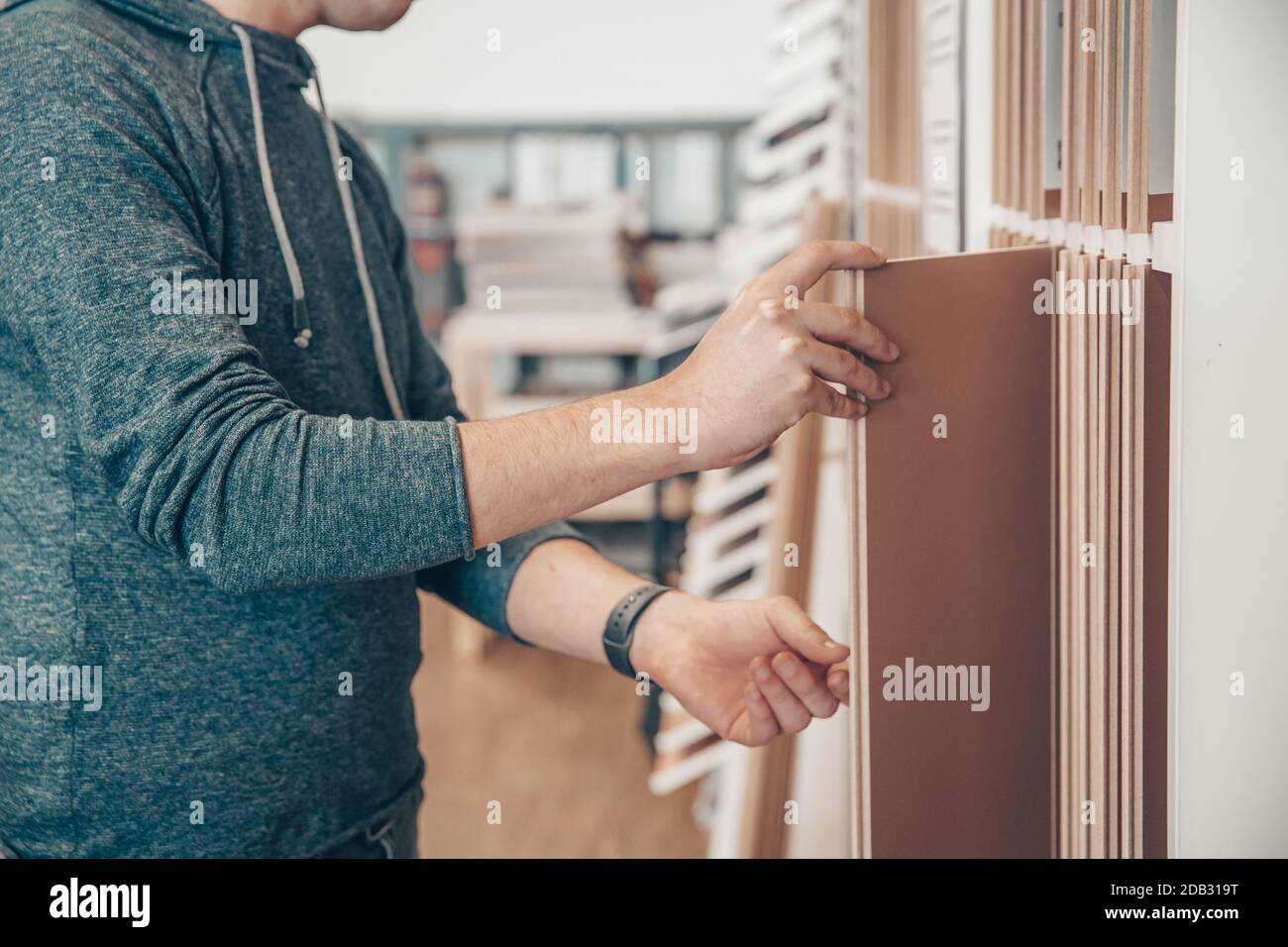 Male selects wooden floor of the sample in the specialized trade. Stock Photo