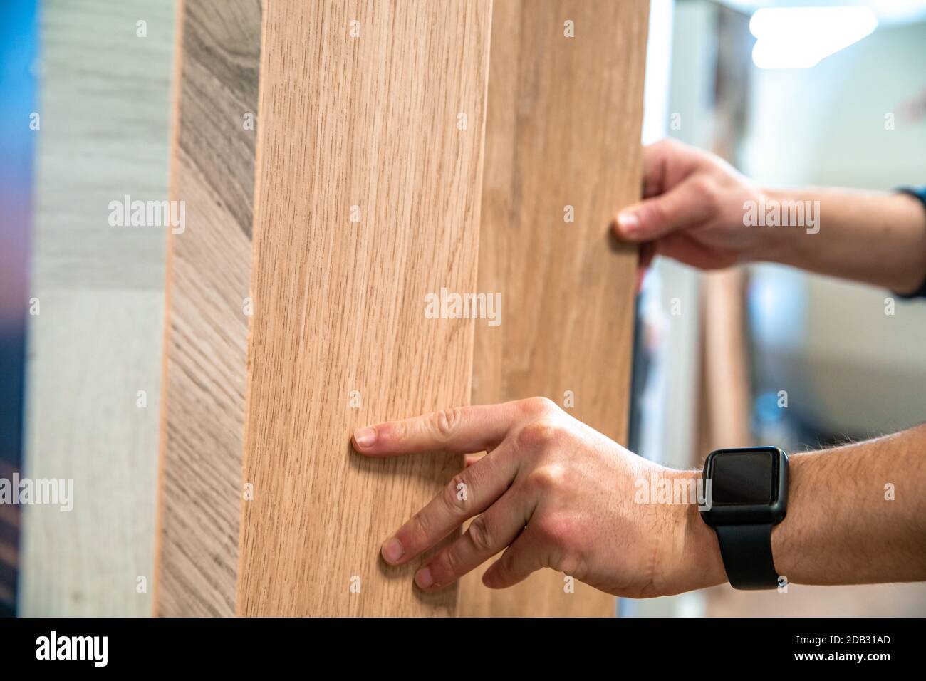 Male selects wooden floor of the sample in the specialized trade. Stock Photo