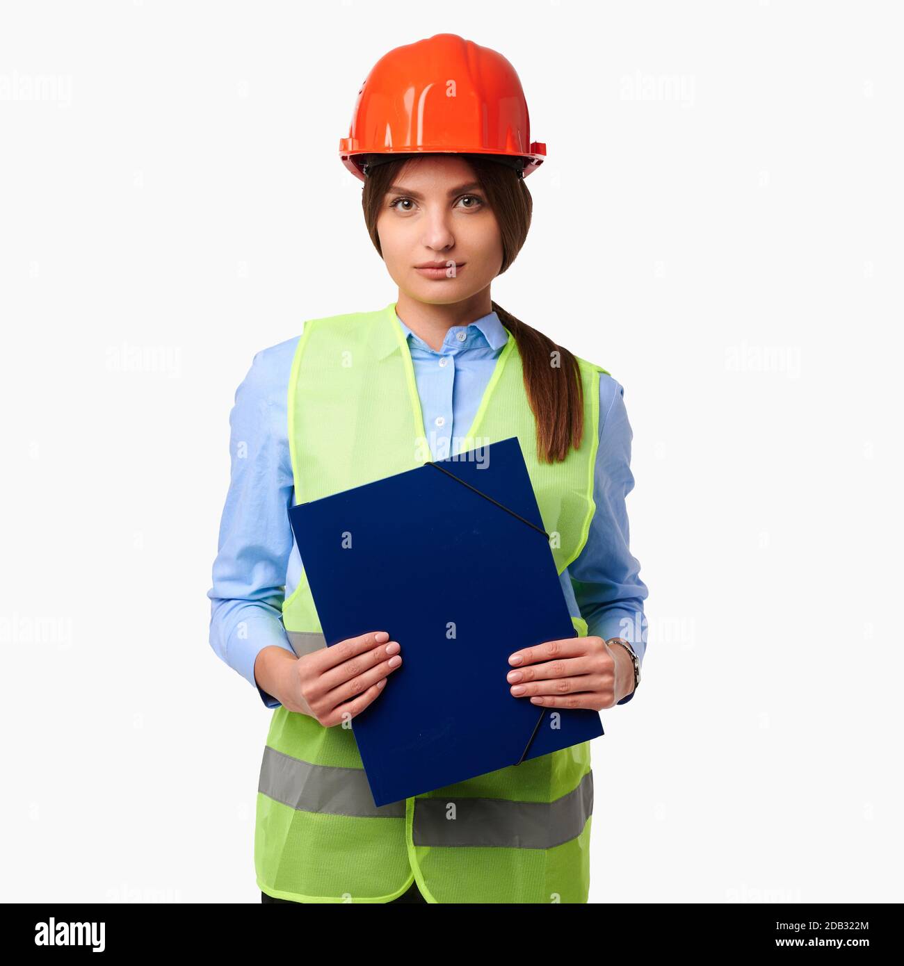 Female engineer in protective helmet and a green vest holding folder on white isolated background Stock Photo